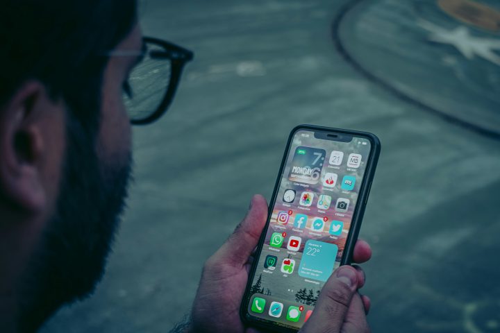 Homme qui fait défiler le fil d'actualité de son téléphone, là où s'affichent les publicités Facebook
