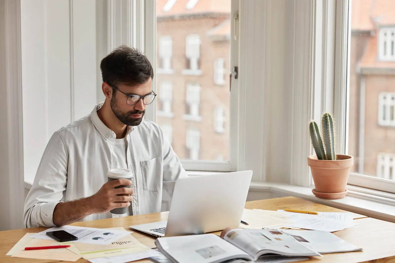 Homme qui travaille sur son ordinateur portable dans un bureau lumineux, en comparant ses stratégies de visibilité en ligne