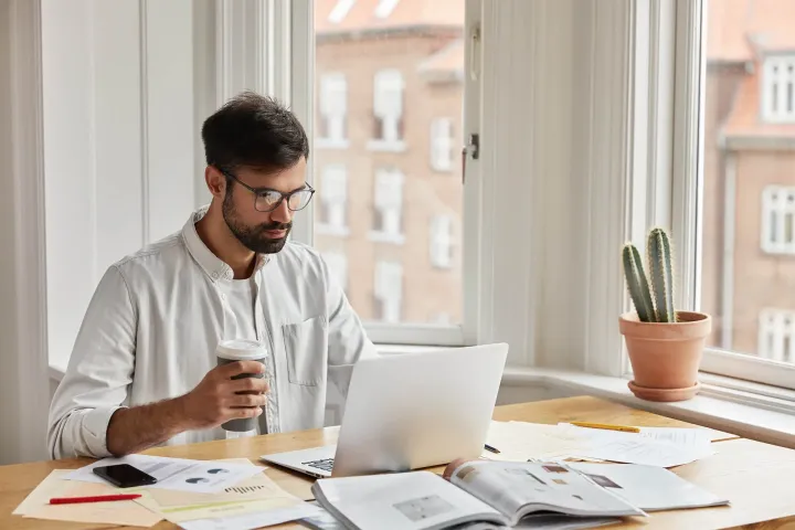 Homme qui travaille sur son ordinateur portable dans un bureau lumineux, en comparant ses stratégies de visibilité en ligne