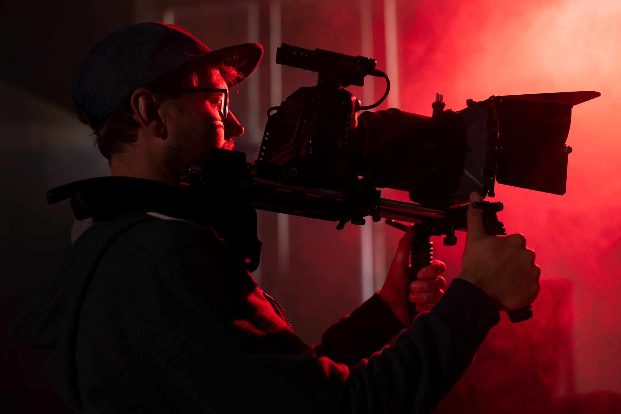 Vidéaste avec une caméra cinéma sous un éclairage rouge pendant un tournage