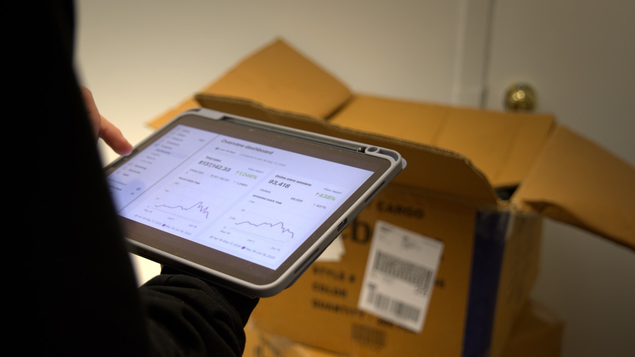 Tableau de bord des ventes en ligne sur une tablette, au-dessus d'un colis